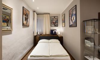 A simple bedroom with a bed and decorative posters on the walls. The atmosphere is cozy and inviting.