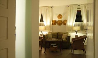 An inviting living room with a cozy couch and two lamps. Decorative plates hang on the wall, and the curtains let soft light shine in.