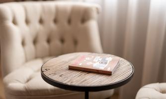 A cozy armchair with a round table. On the table lies a book.