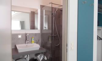 A modern bathroom with a glass shower and a sink. Towels and toiletries are neatly arranged.