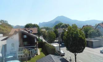 A quiet residential area with a clear view of a hill in the background. There are trees and a few houses in the image.