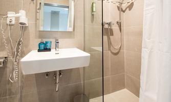 A modern bathroom with a shower, a sink, and a large mirror. Pleasant color scheme with practical care products.