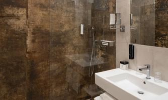A modern bathroom with a glass shower cubicle and an elegant sink. The walls are designed in warm earth tones.