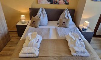 A cozy bedroom with a double bed and decorative pillows. Soft bathrobes are placed on the bed, and the lighting is gentle.