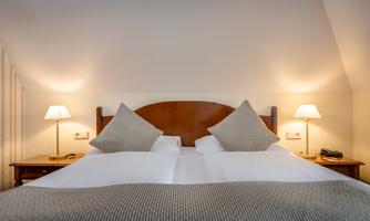 A cozy bedroom with a large double bed and soft lighting. The pillows are decorative and the bedding is inviting.