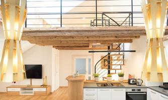 A modern kitchen with wooden elements and large windows. In the background, there is a staircase leading to an upper floor.