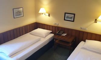 A simple room with two single beds. On the wall hang some pictures and there is a small table with a telephone.