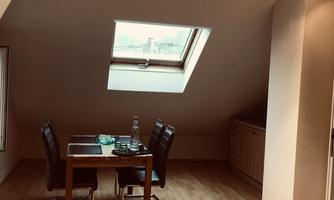 A cozy dining area with a table and chairs. A sloped ceiling with a window provides pleasant light.