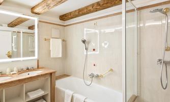 A modern bathroom with a bathtub and a separate shower. Bright tiles and natural wood beams give the space an inviting atmosphere.