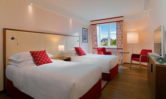 A cozy room with two single beds and beautiful, bright furnishings. Large windows ensure plenty of daylight and a pleasant atmosphere.