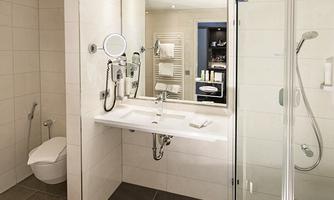 A modern bathroom with bright tiles and elegant sanitary facilities. It features a shower, a sink, and a mirror.