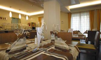 A modern restaurant with elegant tables and stylish decor. The tables are set with cutlery and glasses, and the room is bright and inviting.