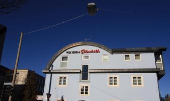 A blue building with a curved roof and the inscription "City" is visible. The sky is clear and blue.