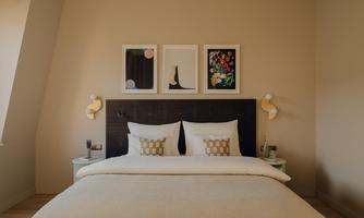 An elegant bedroom with a comfortable bed and stylish wall art. Subtle colors create an inviting atmosphere.