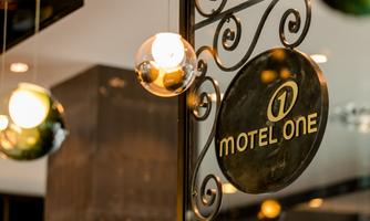 A modern sign of the hotel "Motel One" with stylish lights in the background. The atmosphere is inviting and contemporary.