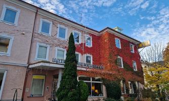 The hotel building with a facade partially covered by red-leaved wild wine. The sky is clear and blue, creating an inviting atmosphere.