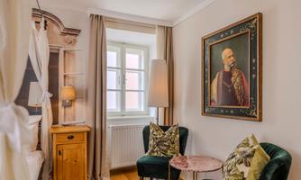 An elegant room with a cozy seating area and a large painting on the wall. The decor is stylish and inviting.