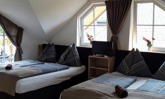 A cozy bedroom with two beds and large windows. The decor is modern and inviting, ideal for a relaxing stay.