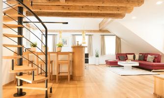 A modern apartment with an elegant spiral staircase and wooden floors. The room is bright and friendly, featuring a cozy seating area and plenty of natural light.