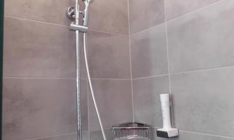 A modern shower with a large rain shower and a convenient handheld showerhead. The walls are designed with gray tiles.