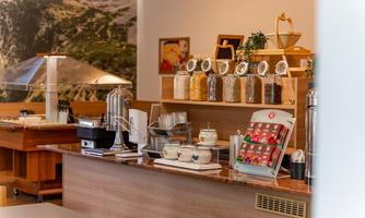 A modern café bar with various drink and snack options. The area is bright and inviting, perfect for a cozy break.