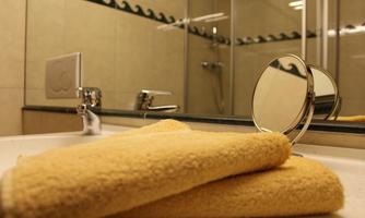 A bathroom with a sink and a large mirror. Yellow towels are placed on the sink.