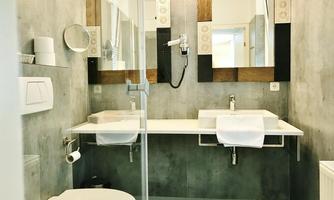 A modern bathroom with two sinks and large mirrors. The walls are done in neutral tones and the decor appears stylish and functional.