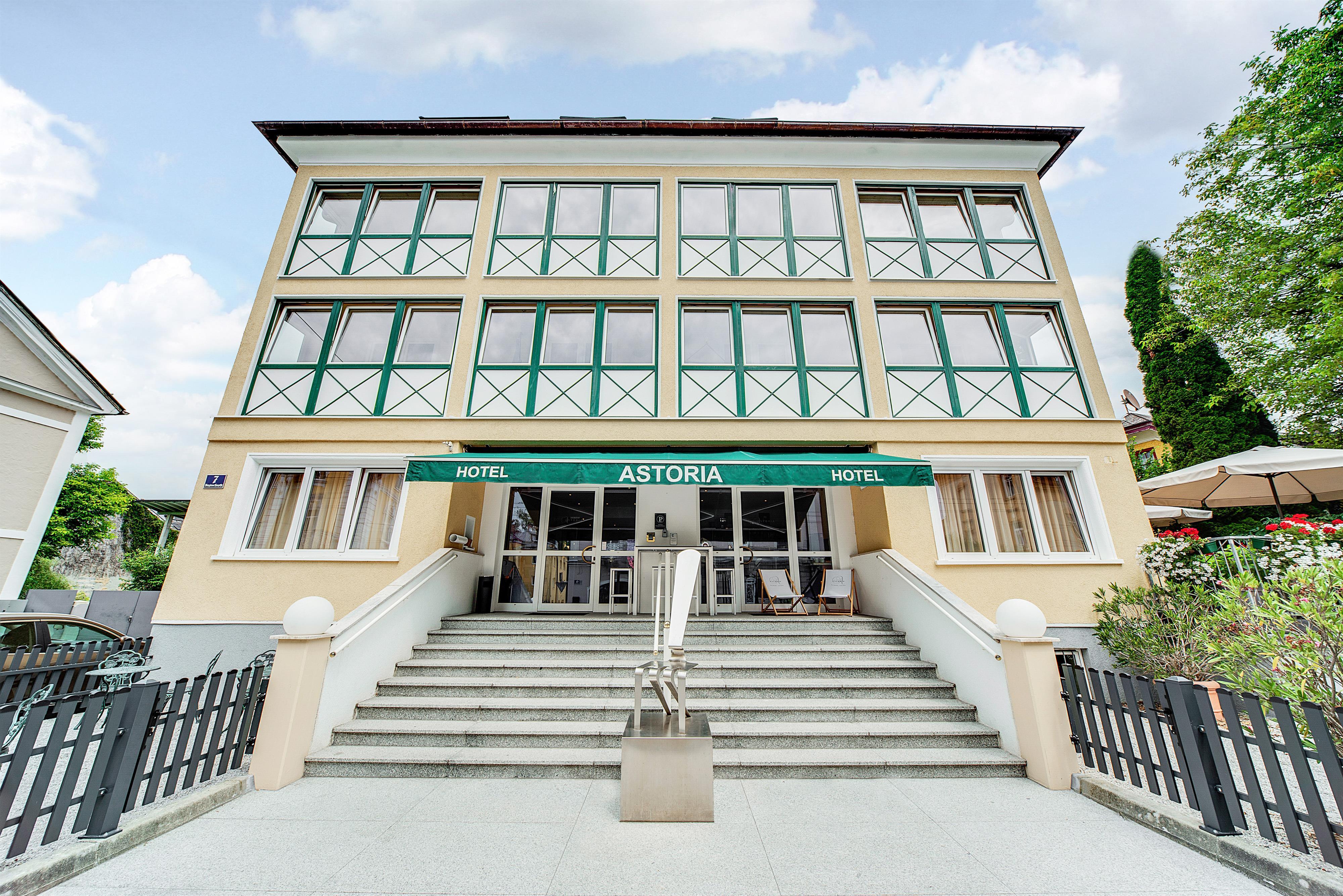 A modern hotel building named "Astoria" at the front. It has large windows and an inviting staircase.