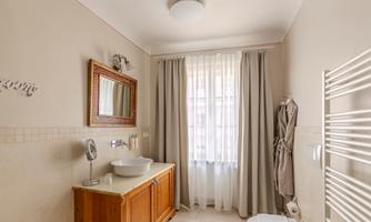 A bright bathroom with a modern sink and a large mirror. The windows let in plenty of daylight and there is a warm, inviting atmosphere.