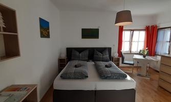 A cozy bedroom with a large bed and modern furnishings.  
Window curtains in bold red create an inviting atmosphere.