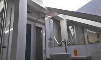 A modern bathroom view with slanted windows. The room features a sink and large mirrors.