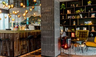 A stylish bar with wooden shelves and cozy seating. The lighting creates an inviting atmosphere.