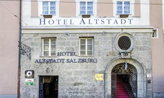 A historic hotel building named "Hotel Altstadt Salzburg." The entrance is welcoming with a red staircase and decorative windows.