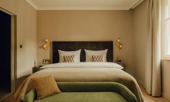 A modern bedroom with a large double bed and tasteful decorative elements. The walls are painted in warm tones, and the room feels inviting and cozy.