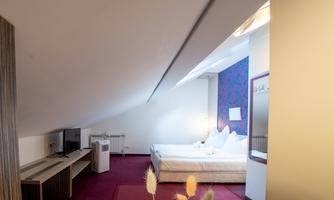 A cozy hotel room with two beds and a modern television. The walls are in soft colors, and the room has an inviting atmosphere.