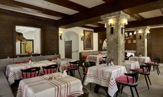 A cozy restaurant with a rustic atmosphere and stylish tables. The tables are set with white tablecloths and red accents.