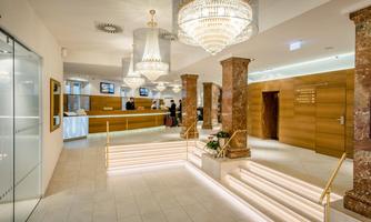 An elegant hotel lobby with modern furniture and tasteful lighting.  
Shiny chandeliers and marble columns give the room a luxurious atmosphere.