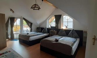 A spacious room with two beds and large windows. It has a modern design and is well lit.