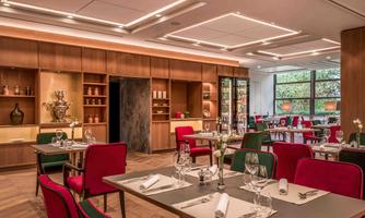 An elegant restaurant with modern furniture in red and green. The tables are set and the ambiance is inviting and warm.