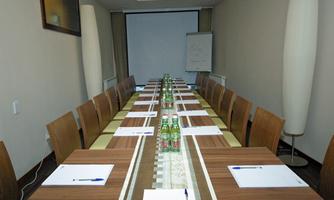 An elegant conference room with a long table and chairs. Notepads and bottles of water are ready on the table.