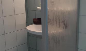A modern bathroom with a shower and a bathtub. The walls are adorned with white tiles, and there is a round shelf.