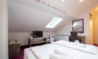 A modern room with two beds, a television, and a desk. Large windows provide plenty of natural light and a pleasant atmosphere.