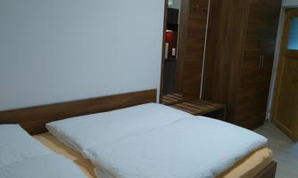 A cozy bedroom with a double bed and a wooden wardrobe. The room has a bright, friendly atmosphere.