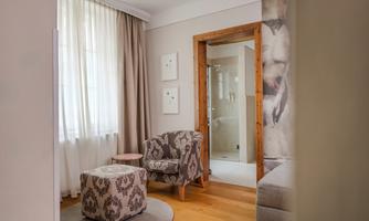 A cozy living space with two chairs and a small table. A lot of daylight pours into the room through the curtains.