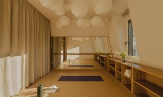 A bright room with large windows used for yoga. Soft colors and round lamps create a relaxing atmosphere.