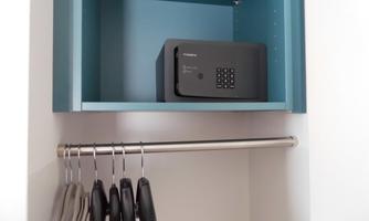 A wardrobe with a safe on the top level and a clothes rail underneath. The clothes rail holds several hangers.