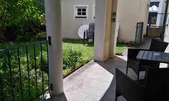 A cozy outdoor area with a small lawn and two modern garden furniture pieces. The sun is shining and there is a relaxed atmosphere.