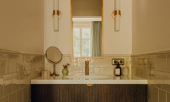 An elegant bathroom with a modern sink and a large mirror. There is stylish lighting and decorative elements that create a pleasant atmosphere.