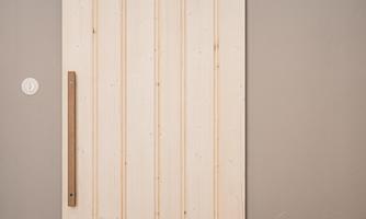 An elegant sliding door made of wood with a modern black track. The background is kept simple and neutral.