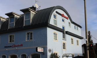 A blue building with a curved roof and several windows. On the facade is the inscription "Pension Glaubeck."